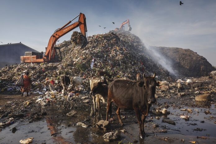 White thick smoke with methane gas seeps up between layers of garbage and waste at the dumping zone of Belgharia in Jharia, Kolkata, West Bengal, India