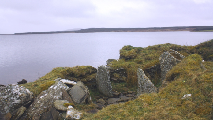 A moss-covered stone tomb on the edge of a coastline in Scotland